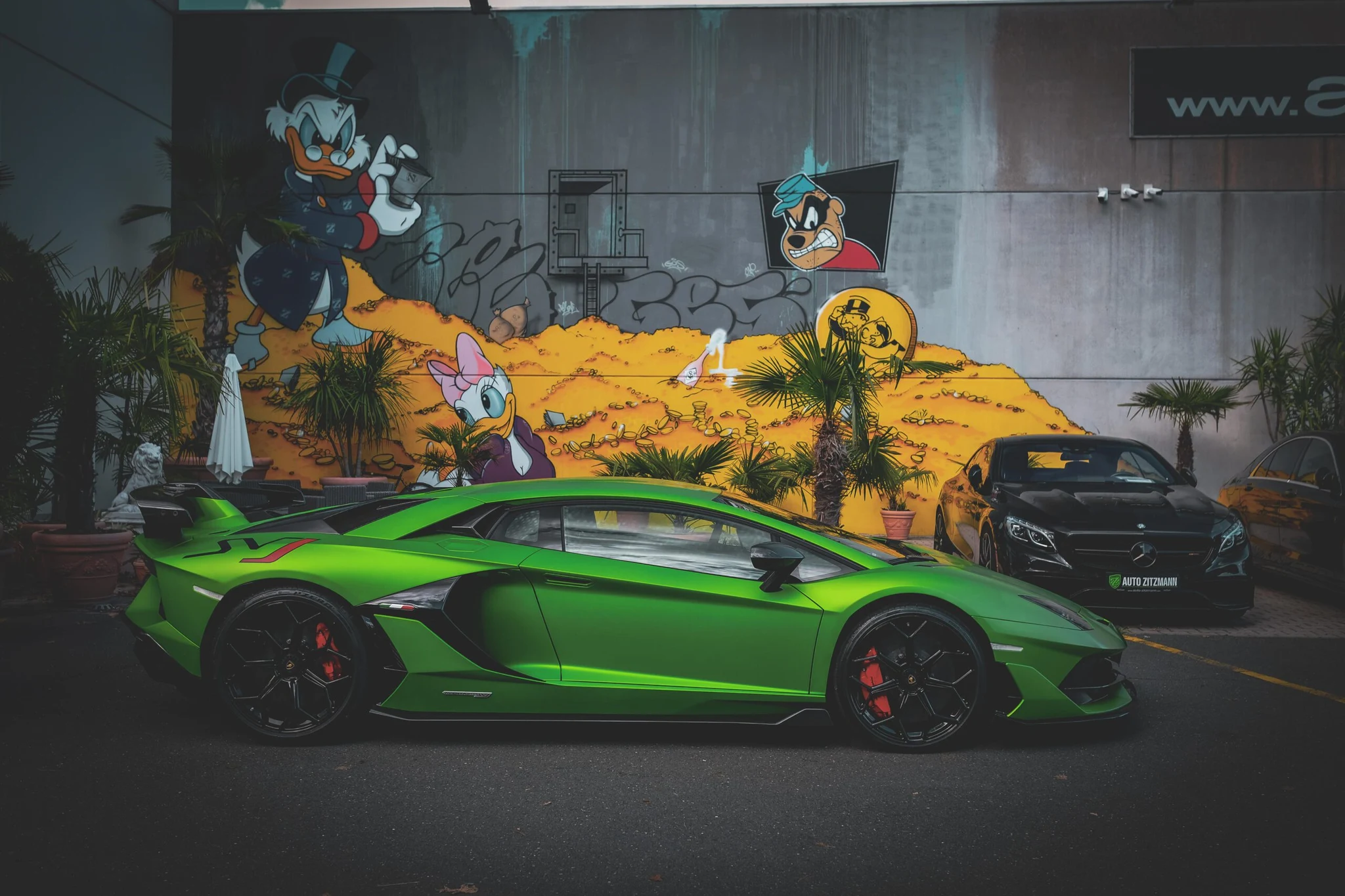 Green Lamborghini Aventador and Mercedes-Benz in the Auto Zitzmann courtyard in Nürnberg, photographed on the dealership’s official website.