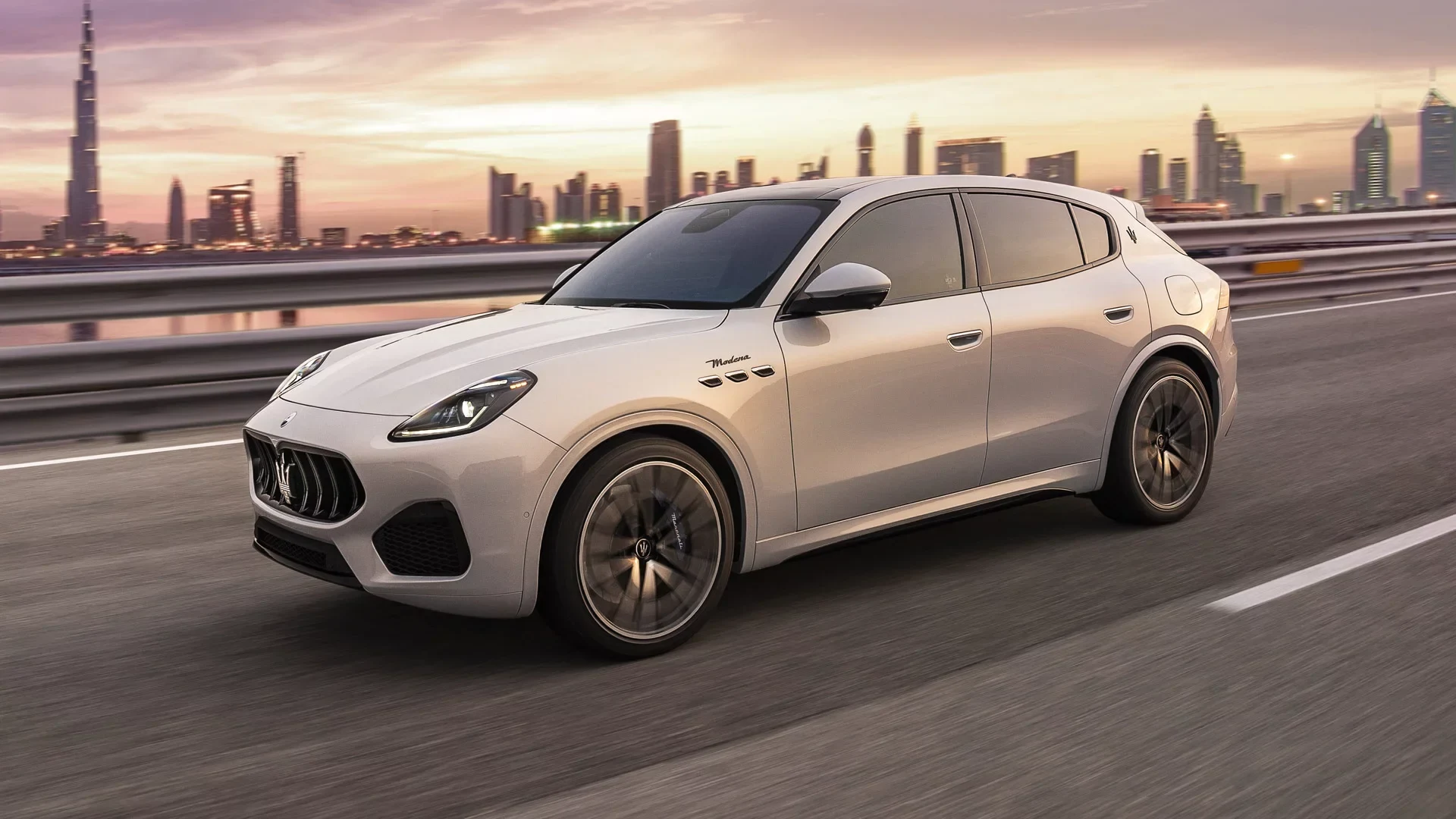 Official Holand cover image showing a white Maserati Grecale Modena on a road against an urban skyline.