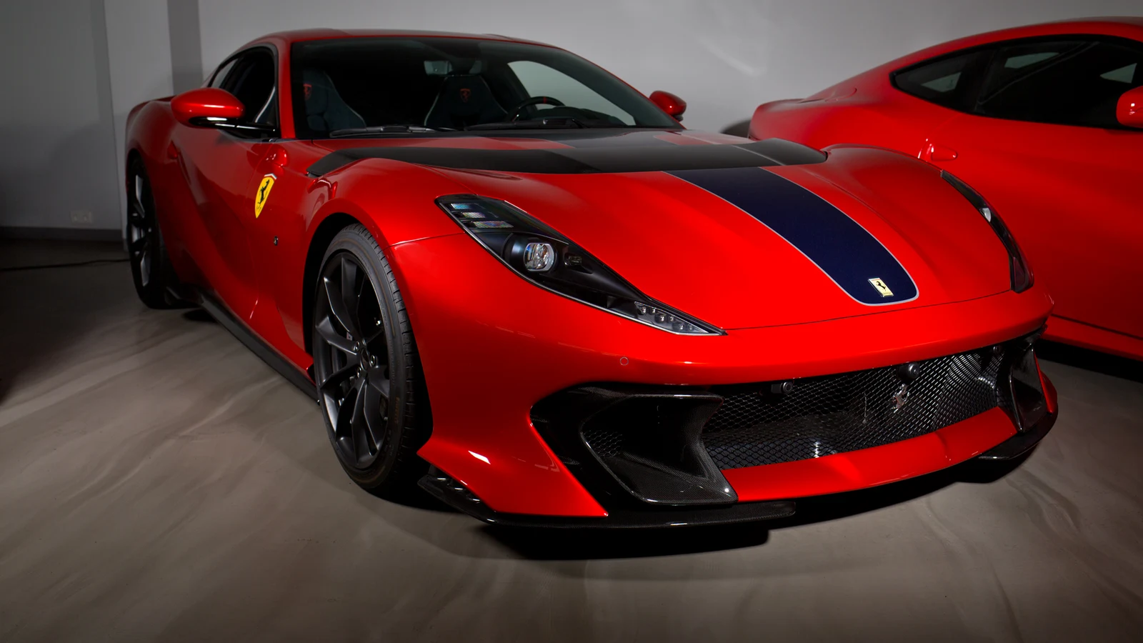 Red Ferrari 812 Competizione with blue stripe, full front three-quarter view